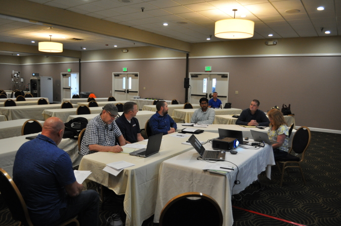 Seven people sit facing the same direction at a rectangular table.