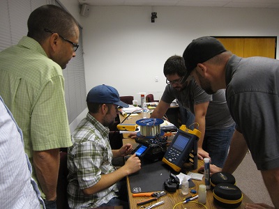 Jeremiah Pearce is in the center working on the District 2 equipment. Watching, left to right: Jeff Worthington, Keith Koeppen, both from District 2, and Will Lyons from District 9.