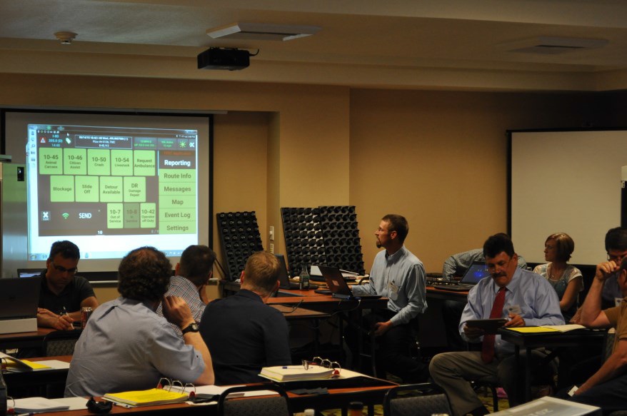 Mark Kelly from the Wyoming DOT demonstrates the tablet reporting app they have developed for road reporting by maintenance personnel. To his right, Ian Turnbull tries out the app on a WYDOT tablet. (2015)