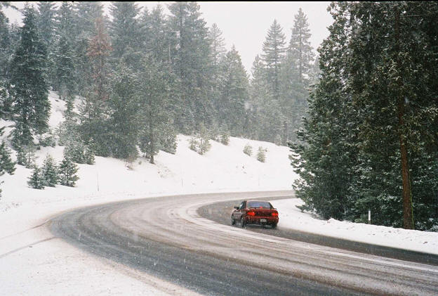 Car takes a curve through Fredonyer Pass in the winter.