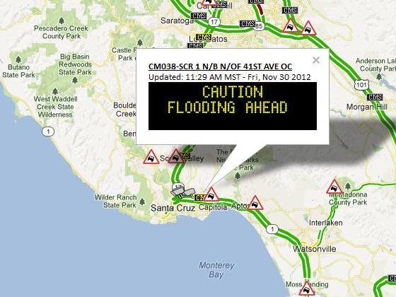 Road warning sign along HWY 1 near Santa Cruz displaying: Caution Flooding Ahead.