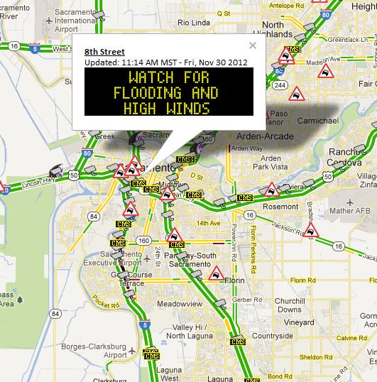Road warning sign at 8th Street in Sacramento displaying: Watch for Flooding and High Winds. 