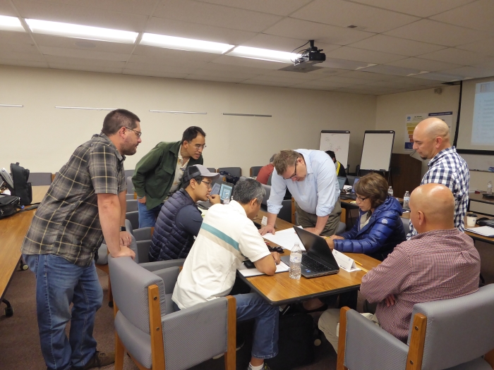 Students gather around course instructor Phil Isaak as he reviews one group's lab exercise.