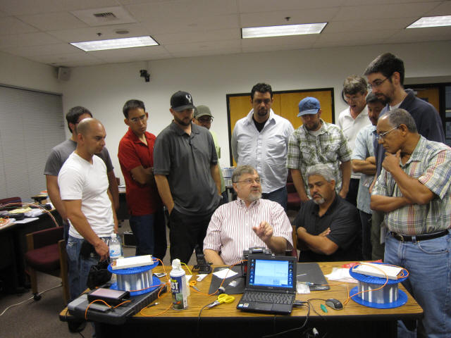 The students in the optical fiber course gather around instructor Eric Pearson to watch the fusion splice demonstration.