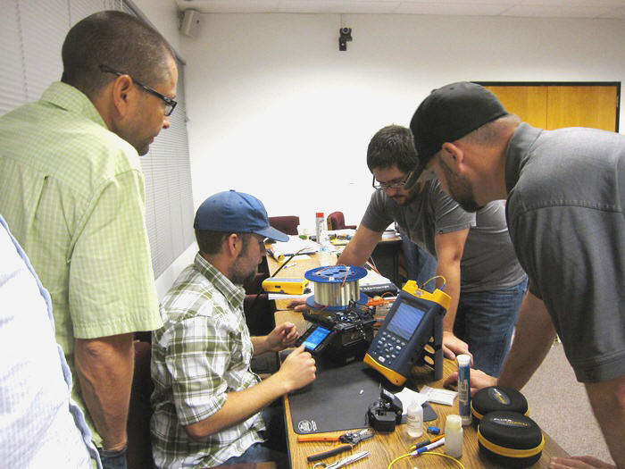 Jeremiah Pearce is in the center working on the equipment.  Watching, left to right:  Jeff Worthington, Keith Koeppen, both from District 2, and Will Lyons from District 9.