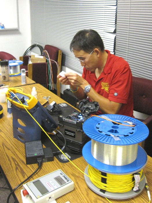 Steven Gee prepares fiber ends before completing a fusion splice.