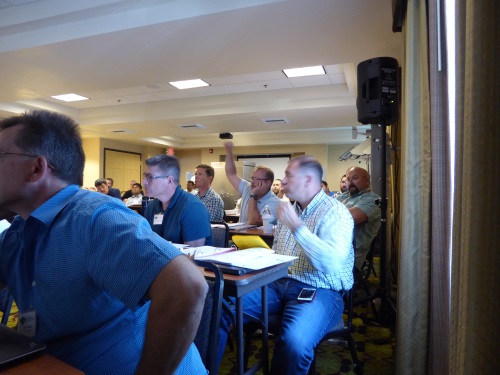 A participant raises their hand to ask for clarification during a presentation.