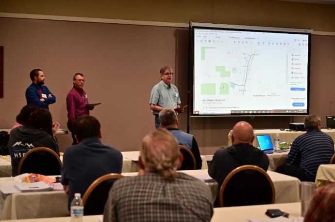 The Forum Steering Committee. Three men stand in front of a projector screen.