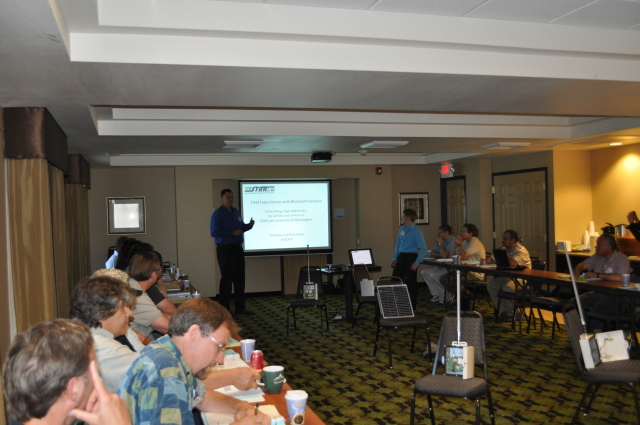 Ted Bailey from the Washington State DOT introduces Yegor Malinovskiy from the University of Washington.  The Bluetooth sensors used to collect travel time information are set up on the chairs in the middle of the room.