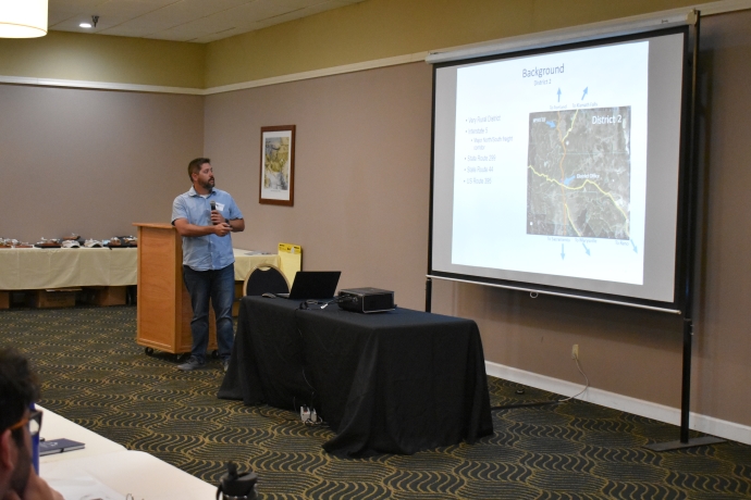 Keith Koeppen A man points at a map image displayed on a projector screen.
