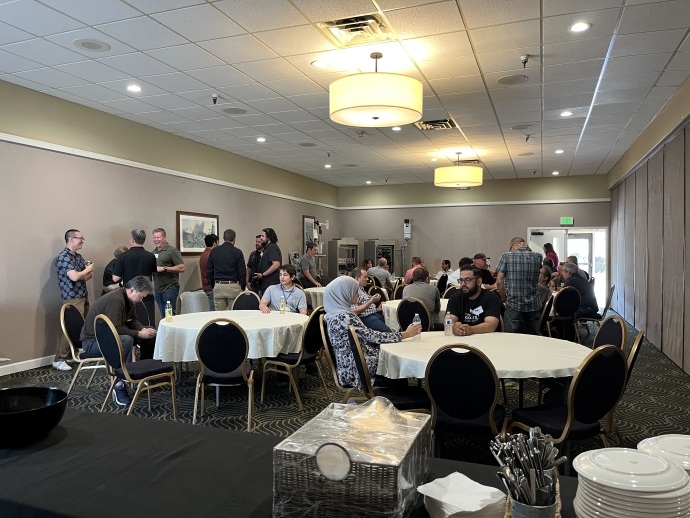 Participants networking at the 2023 Western States Forum Small groups of people talk to one another while standing near equipment and seated at tables.