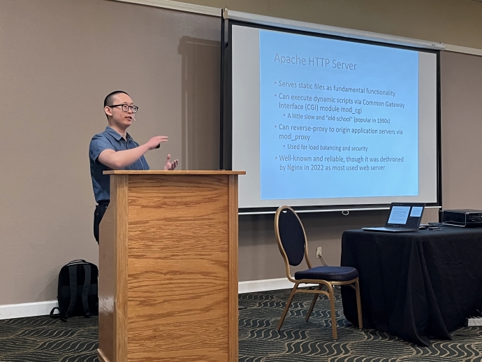 Jared Sun A man stands behind a podium and gestures at a projector screen behind him. Text on the slide includes Apache HTTP Server.