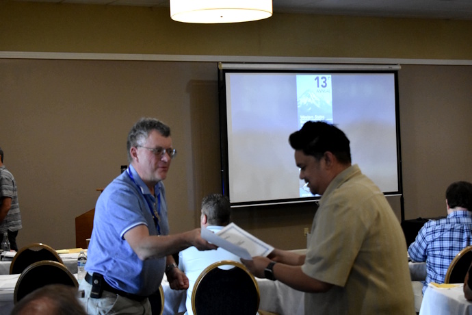 A man hands a certificate to another man.